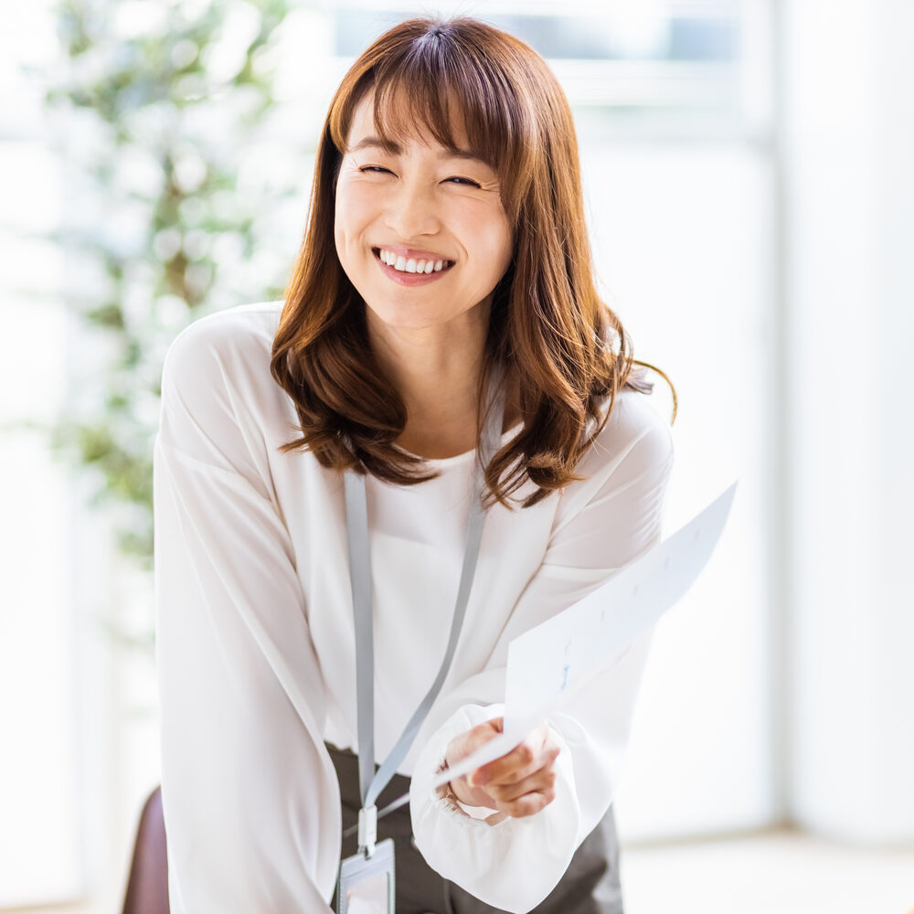 明るいオフィスで書類を手に微笑む女性