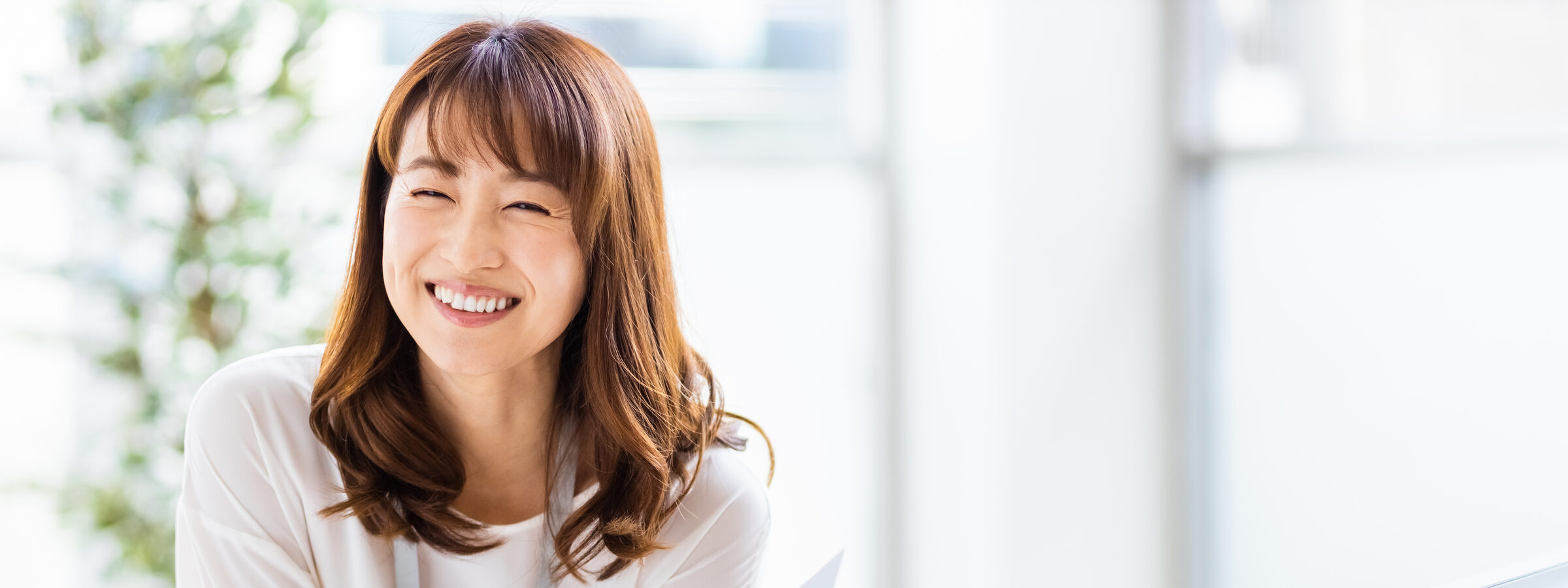 明るいオフィスで書類を手に微笑む女性